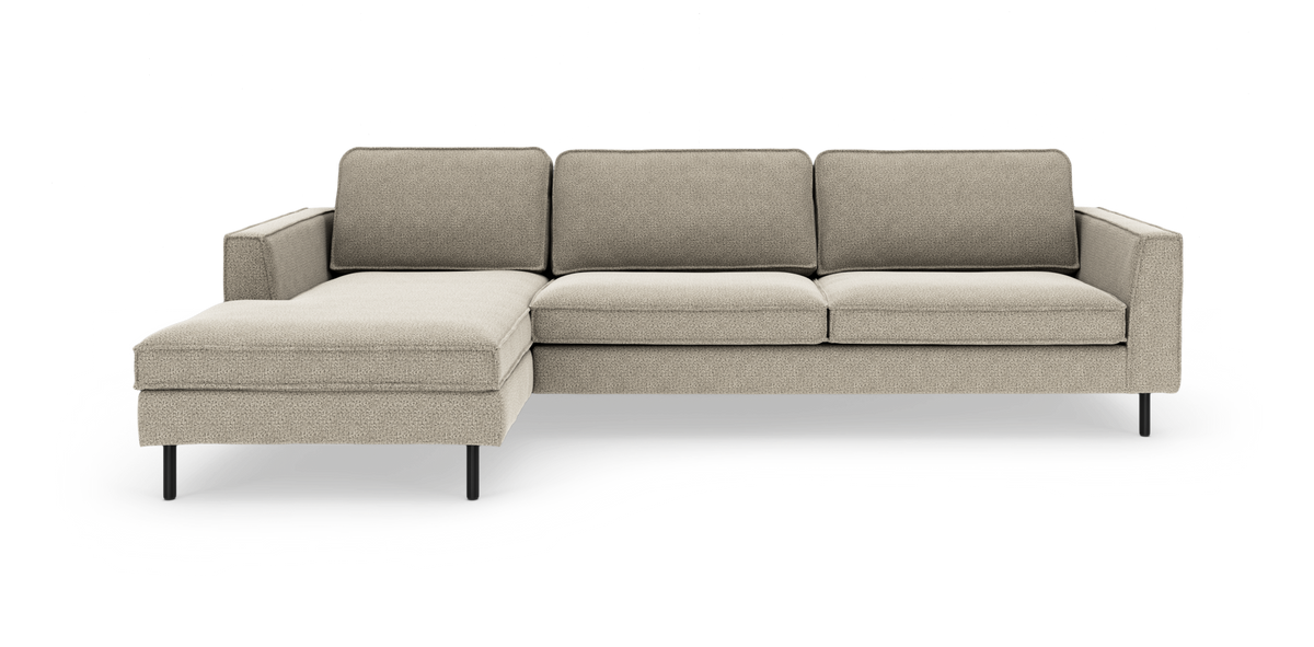 Beige modulsofa med venstrevendt chaiselong, slanke sorte ben og moderne minimalistisk design i studiemiljø.