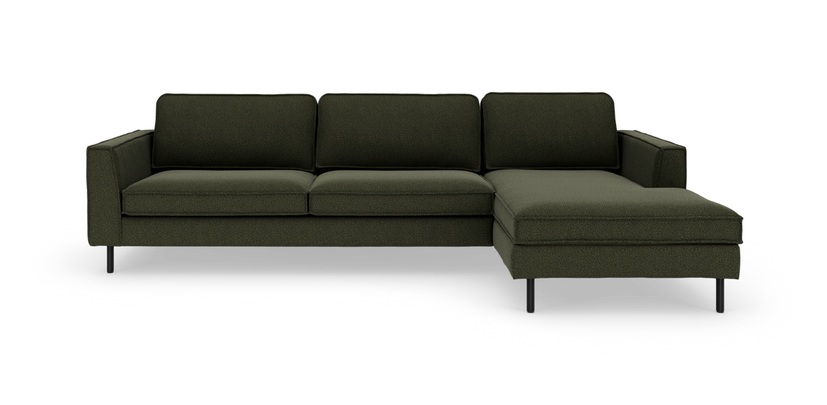Mørkegrøn hjørnesofa med chaiselong til højre og slanke sorte ben på ren studiebaggrund.