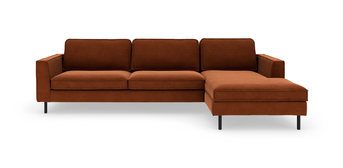 Modulsofa i rustbrunt stof med højrevendt chaiselong og slanke sorte ben, frilagt på hvid baggrund.