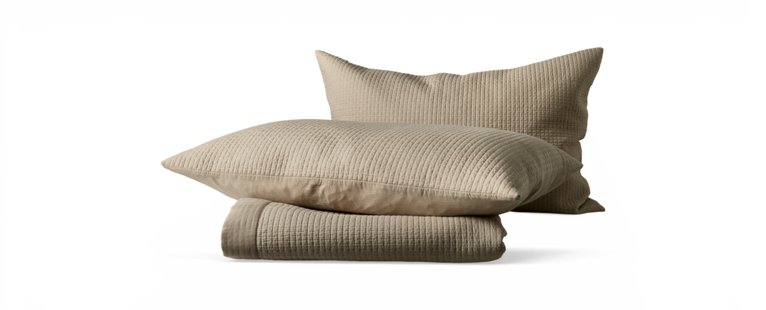 Beige quiltede puder med matchende foldet sengetæppe.