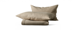 Beige quiltede puder med matchende foldet sengetæppe.