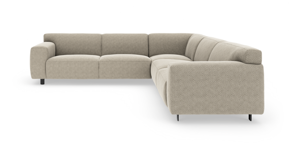 L-formet modulsofa i lys beige stof med afrundede armlæn og slanke sorte ben, frilagt på hvid baggrund.