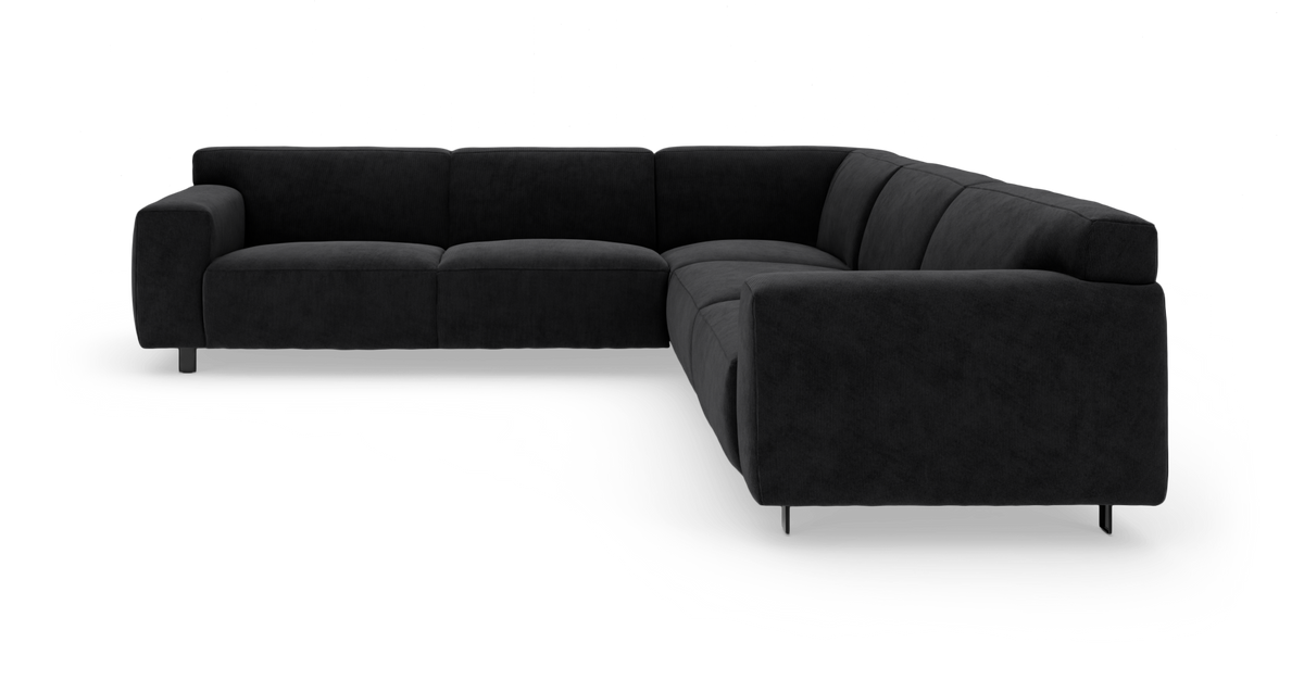 Sort L‑formet hjørnesofa med brede armlæn og lave metalben, vist i studie mod hvid baggrund.