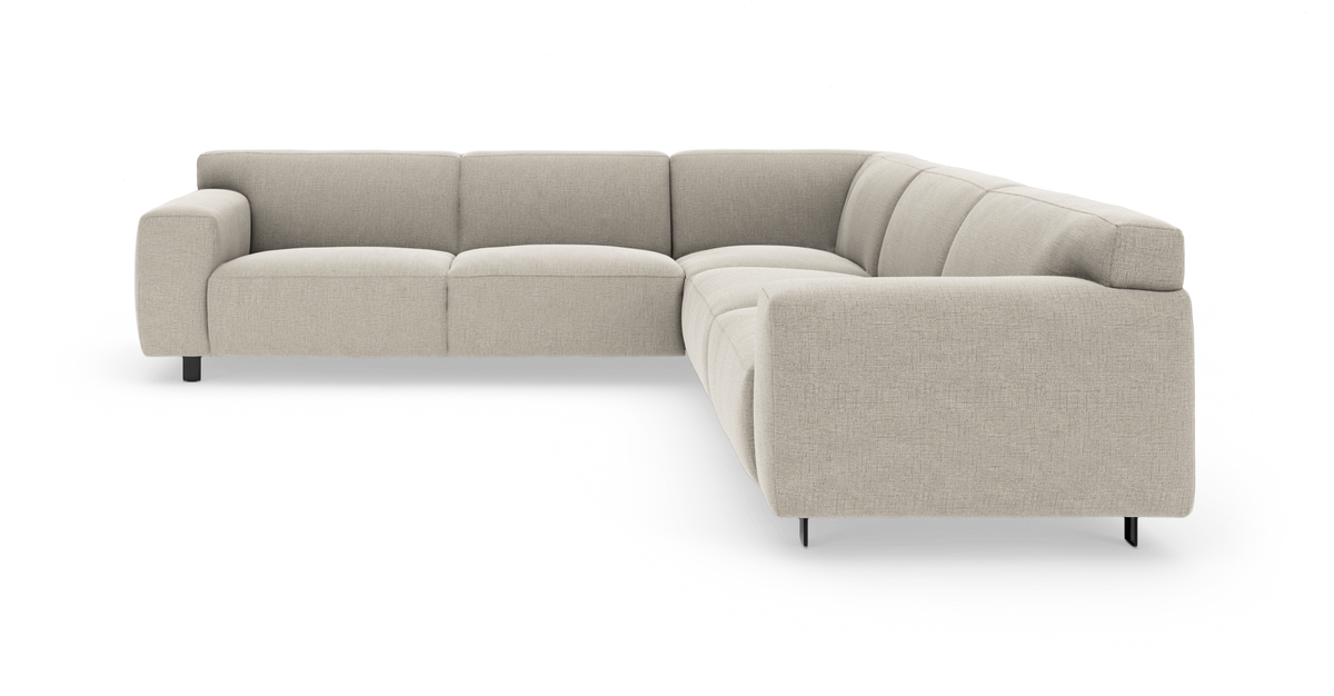 Beige L‑formet modulsofa i stof, frilagt på hvid baggrund.