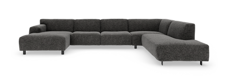 Mørkegrå L-formet modulsofa med lav ryg og metalben, fotograferet i studie mod neutral sort/hvid baggrund.