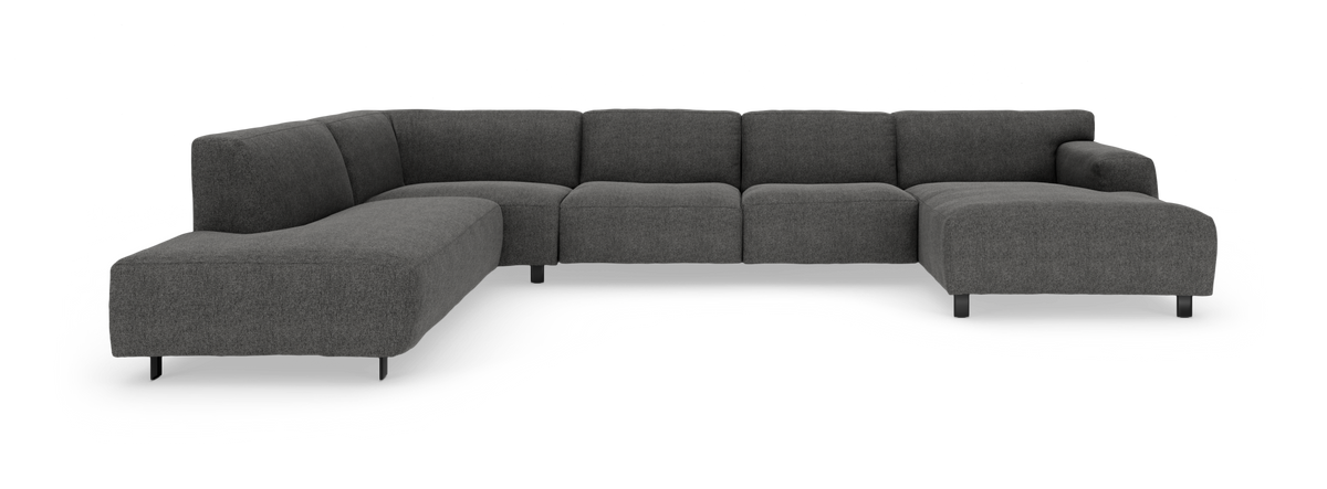 Mørkegrå modulsofa i U-form med lav ryg og slanke sorte ben, fotograferet lige for i studiemiljø.