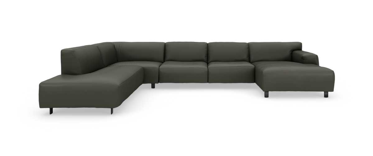 Mørkegrøn modulsofa i U‑form på studiobaggrund.