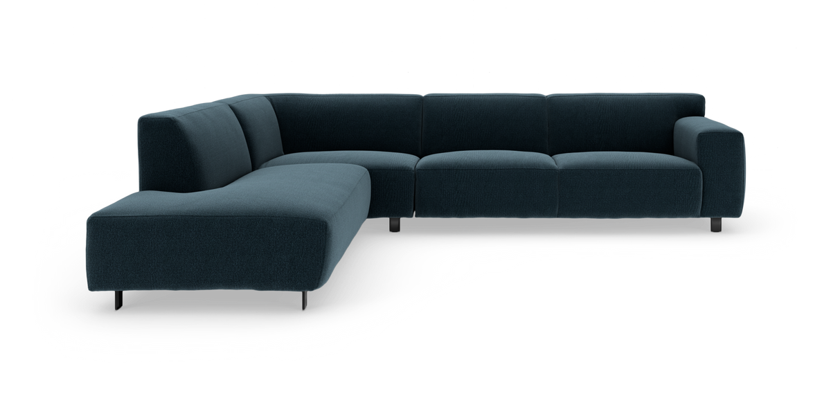 Mørk petroleumblå L‑formet modulsofa med afrundede hynder og slanke metalben, fritlagt på hvid baggrund.