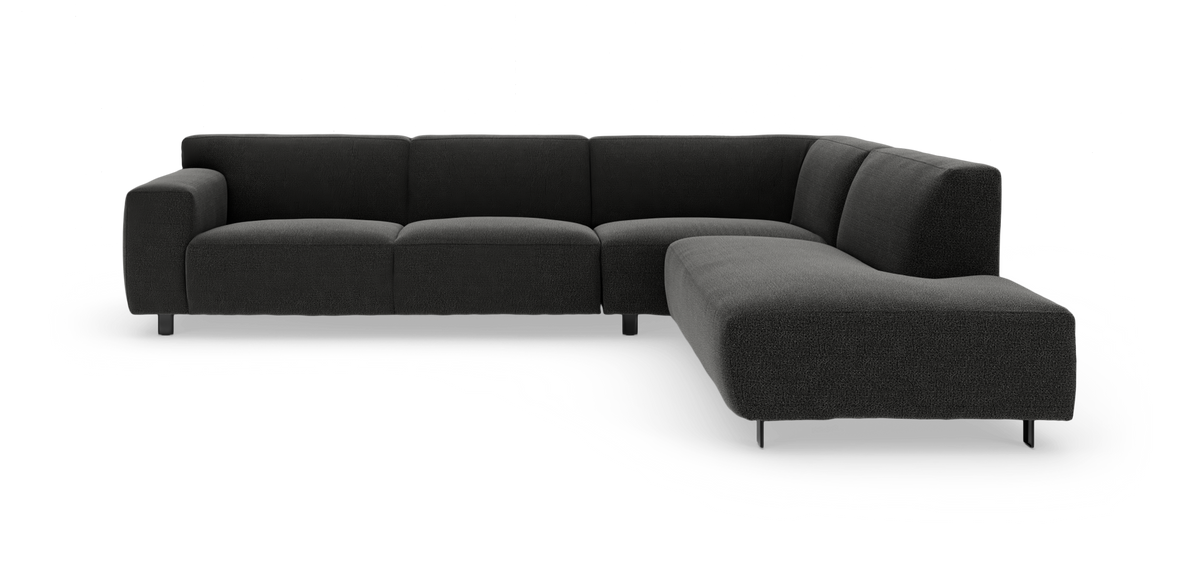 Mørkegrå L‑formet modulsofa med bløde, afrundede puder og metalben, frilagt på hvid baggrund.