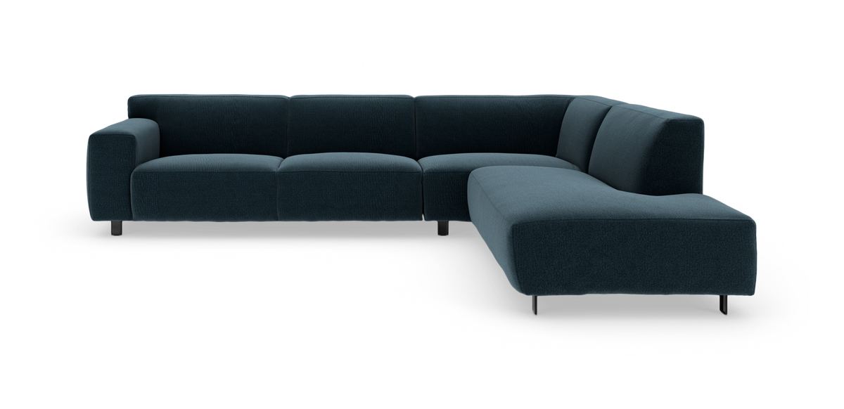 Mørk petrolblå L‑sofa med chaiselong til højre, moderne lav ryg og metalben på hvid baggrund.