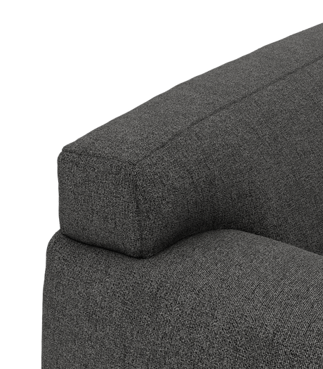 Nærbillede af armlænet og ryglænet på en mørkegrå stofsofa i studiemiljø.