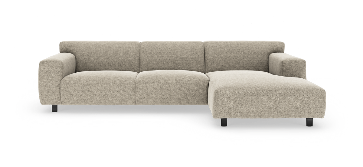 Beige modulsofa med højre chaiselong, bløde brede sædehynder og sorte ben, fritlagt på hvid baggrund.