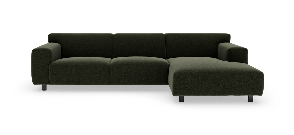 Mørkegrøn modulsofa med chaiselong til højre på hvid baggrund.