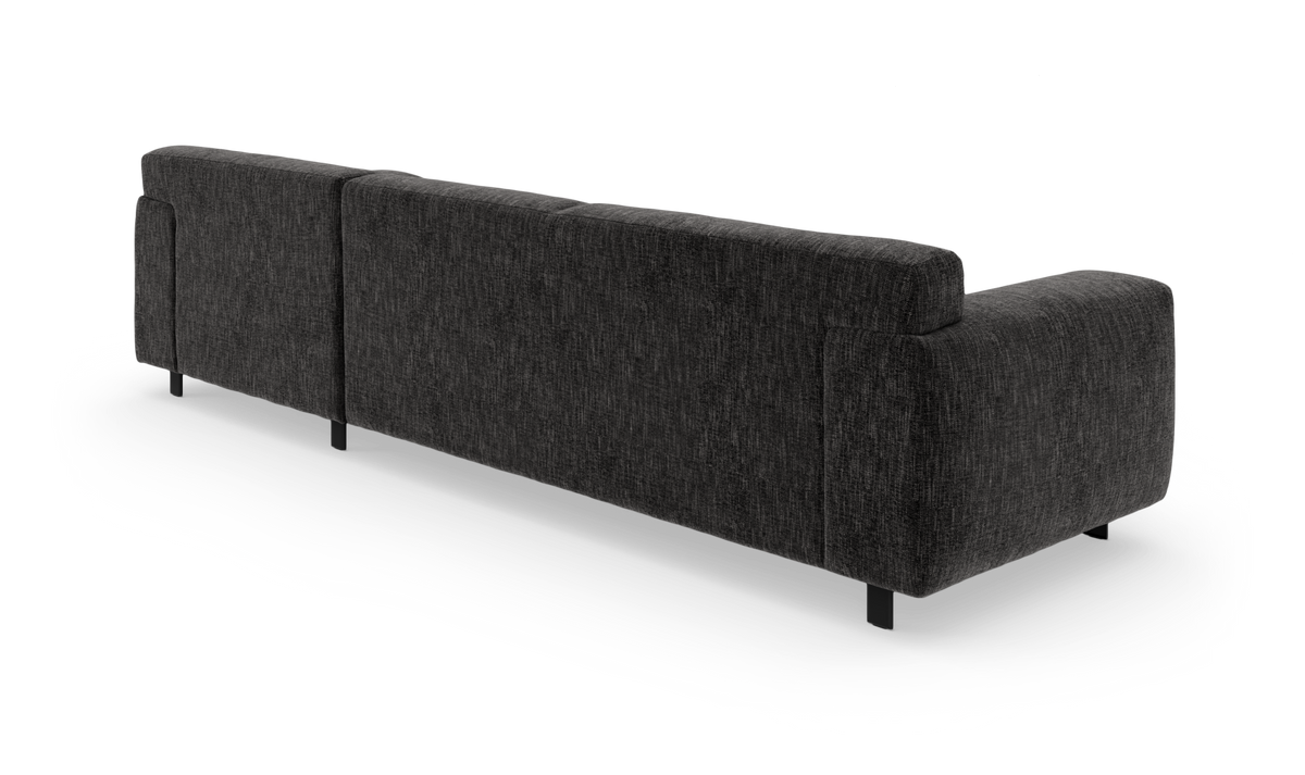 Mørkegrå, moderne stofsofa set bagfra i studiemiljø, let bagvinklet med sorte ben.