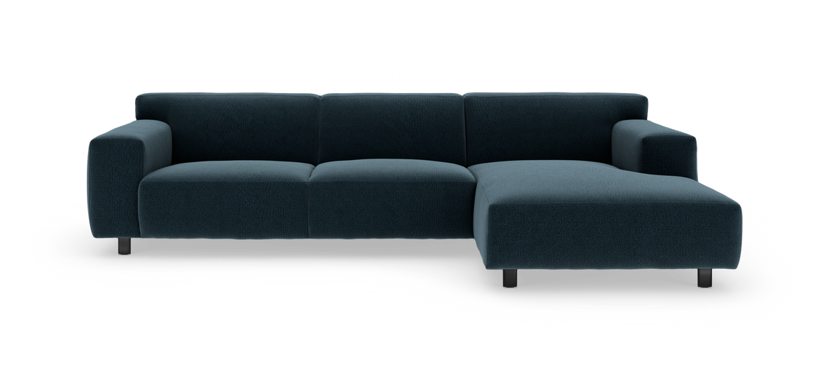 Mørk petrolblå hjørnesofa med chaiselong til højre, på metalben mod hvid studiobaggrund.