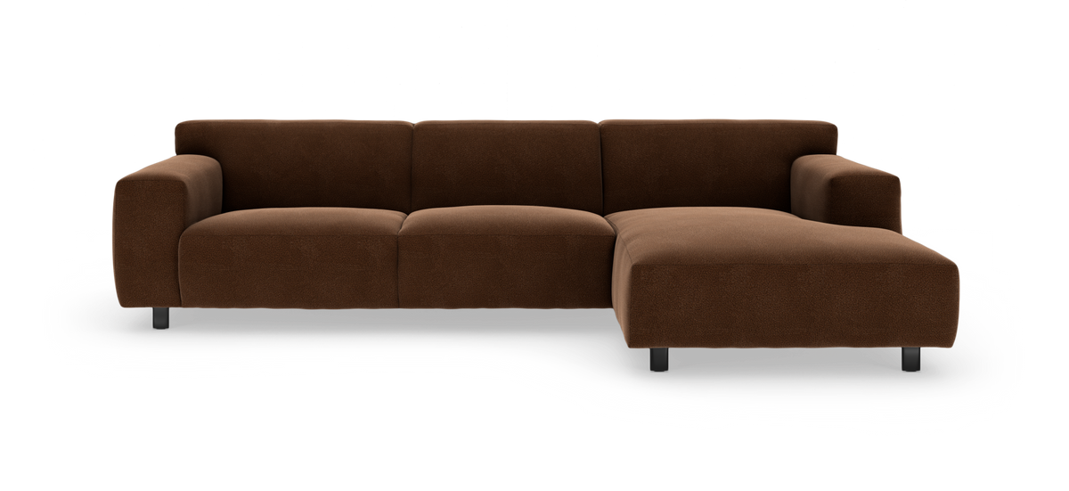 Brun hjørnesofa med chaiselong til højre, bløde afrundede armlæn og metalben, fritlagt på hvid baggrund.