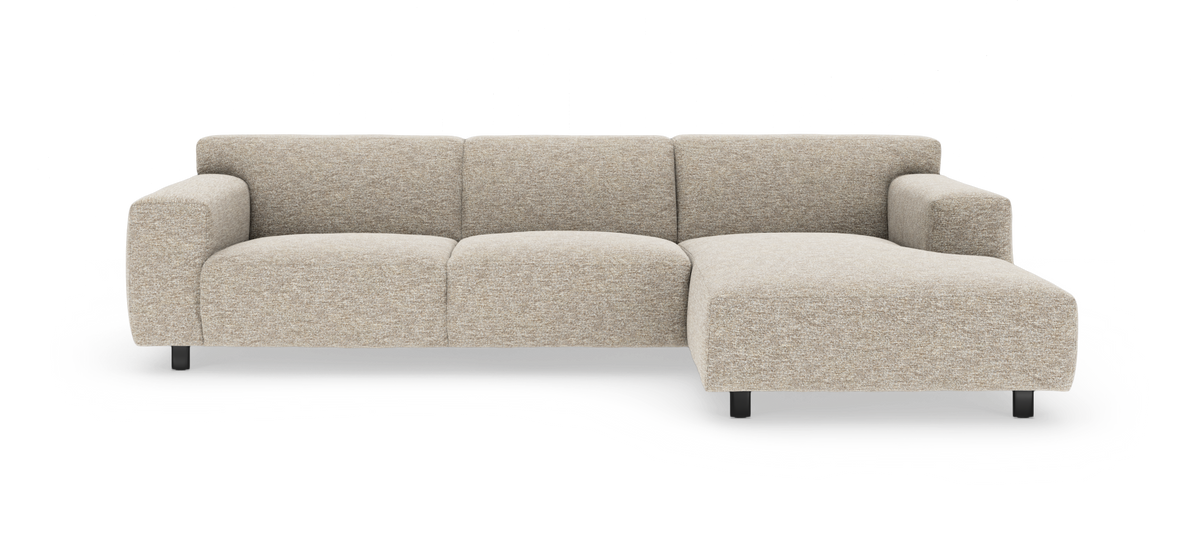 Beige modulsofa med chaiselong til højre, afrundede armlæn og sorte ben, frilagt på hvid baggrund.