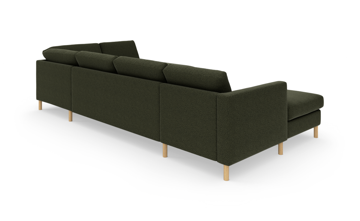 Mørkegrøn modulopdelt hjørnesofa med chaiselong, set bagfra i vinkel med slanke lyse træben.
