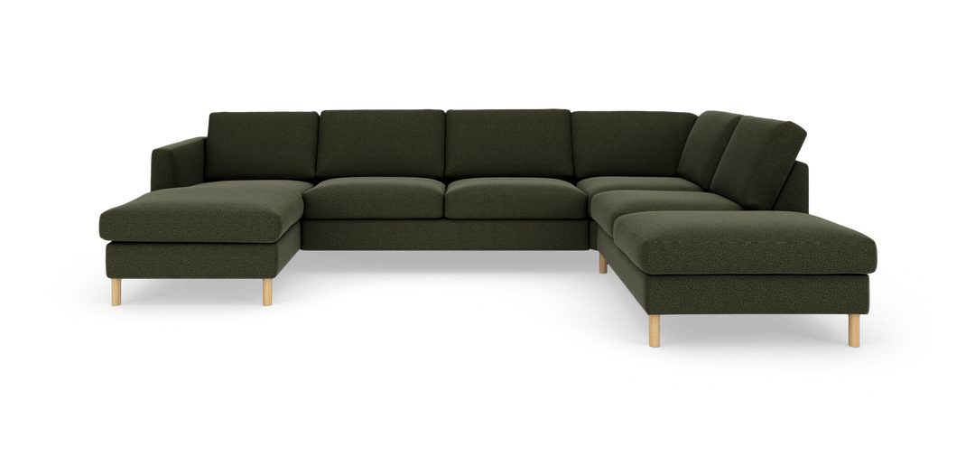 Mørkegrøn modulsofa i U‑form med chaiselong til venstre og divan til højre, med lyse træben.