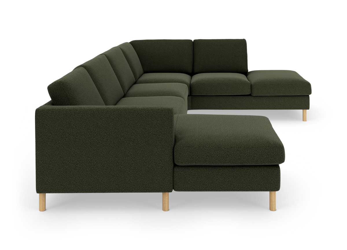 Mørkegrøn modulhjørnesofa i U-form med chaiselong og lyse træben, frilagt på hvid baggrund.