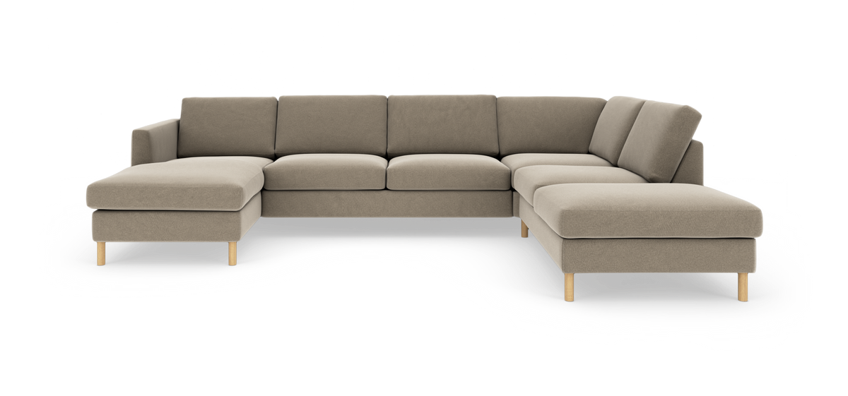 Beige U‑formet modulsofa med chaiselong i begge ender og lyse træben.
