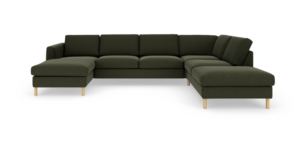 Mørkegrøn L‑formet modulsofa med chaiselong i begge ender og lyse træben, fotograferet mod hvid studiobaggrund.