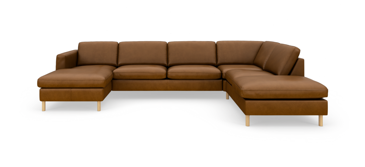 Stor modulsofa i brun læder med chaiselong til venstre og liggedel til højre på lys baggrund.
