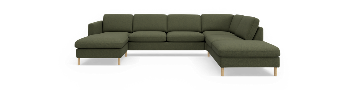 Grøn modulsofa i U‑form med chaiselong i begge ender og træben, fritlagt på sort baggrund.