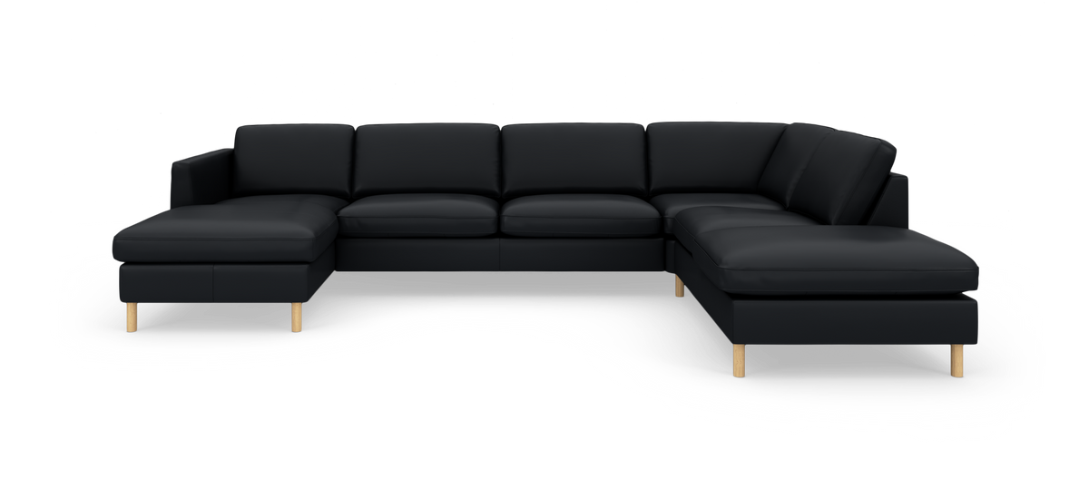 Sort modulsofa i U‑form med chaiselong i begge ender og lyse træben, fotograferet lige for i studie på hvid baggrund.