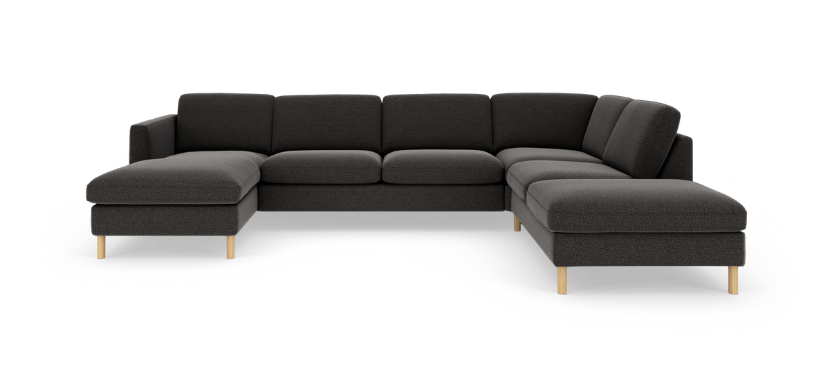 Mørkegrå modulsofa i U‑form med åben chaiselong og lyse træben, frilagt på hvid baggrund.