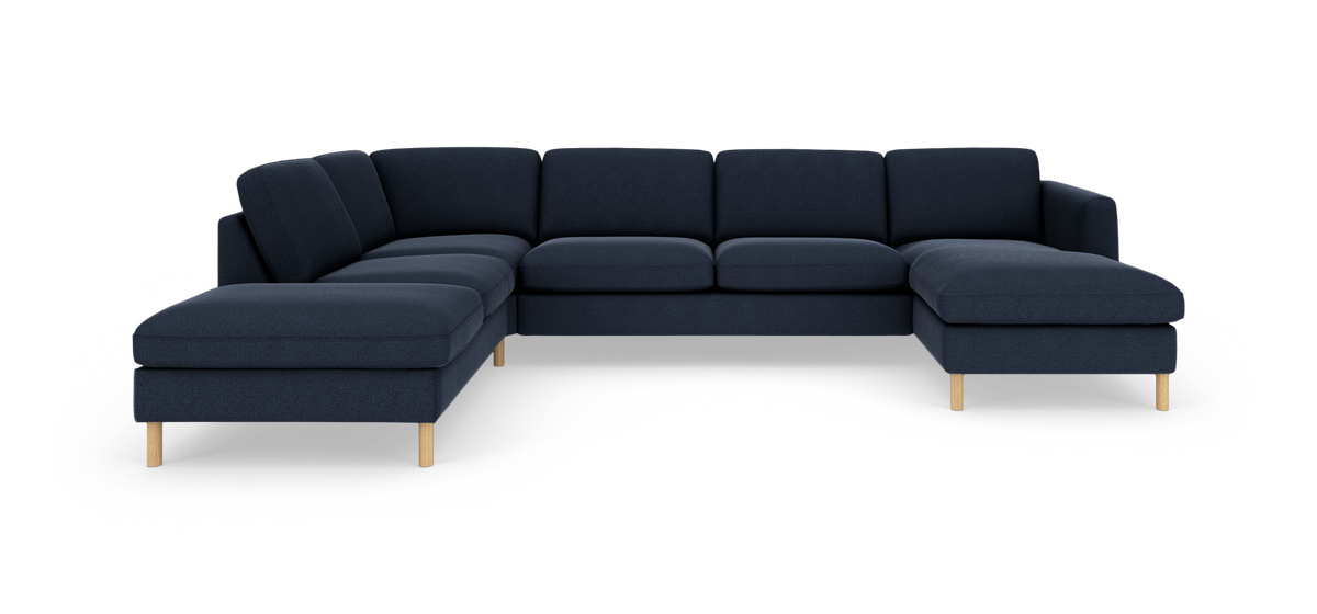 Mørkeblå modulsofa i U‑form med chaiselong til højre og lyse træben, frilagt på hvid baggrund.