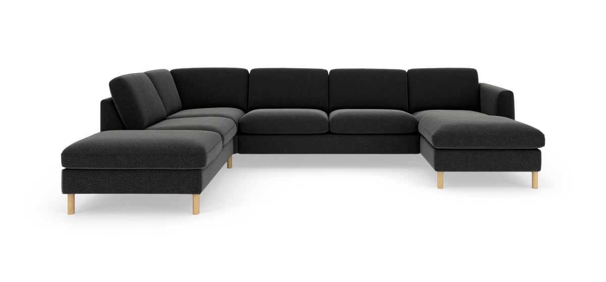 Mørkegrå modulsofa i U‑form med chaiselong til højre og lyse træben på hvid baggrund.