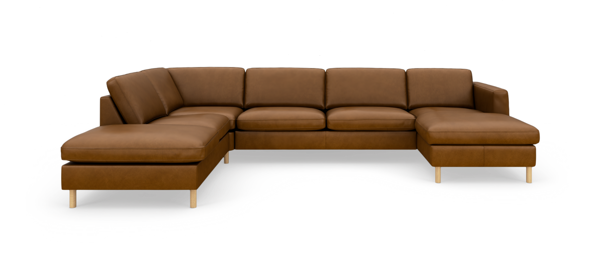 U‑formet hjørnesofa i brunt læder med chaiselong i begge ender og lyse træben, frilagt på hvid baggrund.