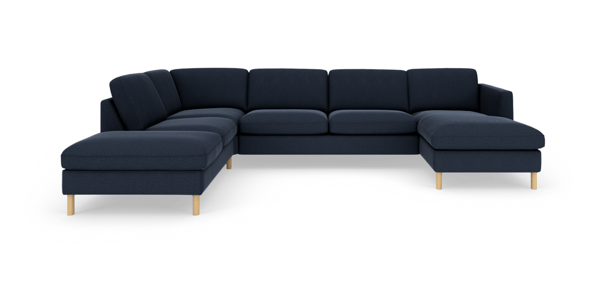 Mørkeblå modulsofa i U‑form med træben, fritlagt i studie.