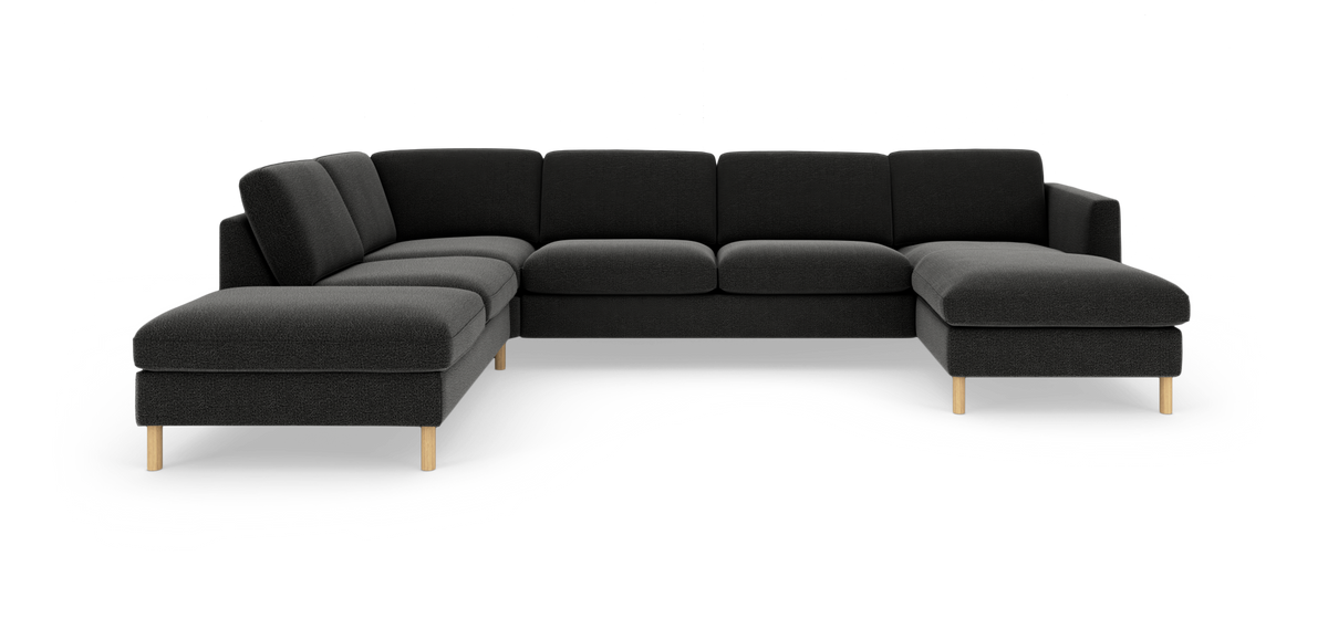 Mørkegrå modulsofa i U‑form med chaiselong til højre og lyse træben på hvid baggrund.