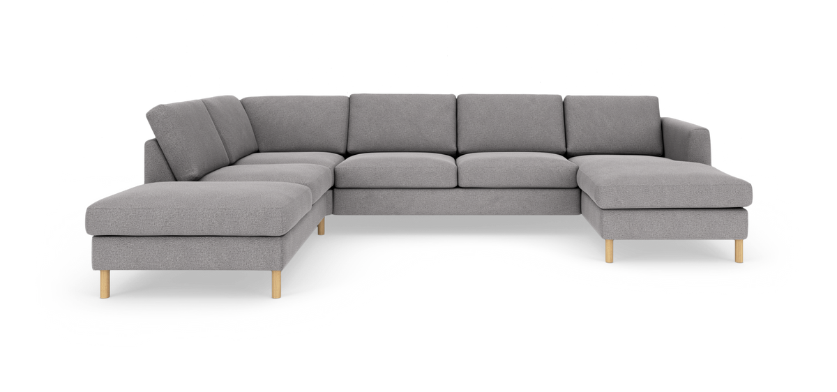 Stor grå U‑sofa i stof med chaiselong til højre og divan til venstre, på lyse runde træben.