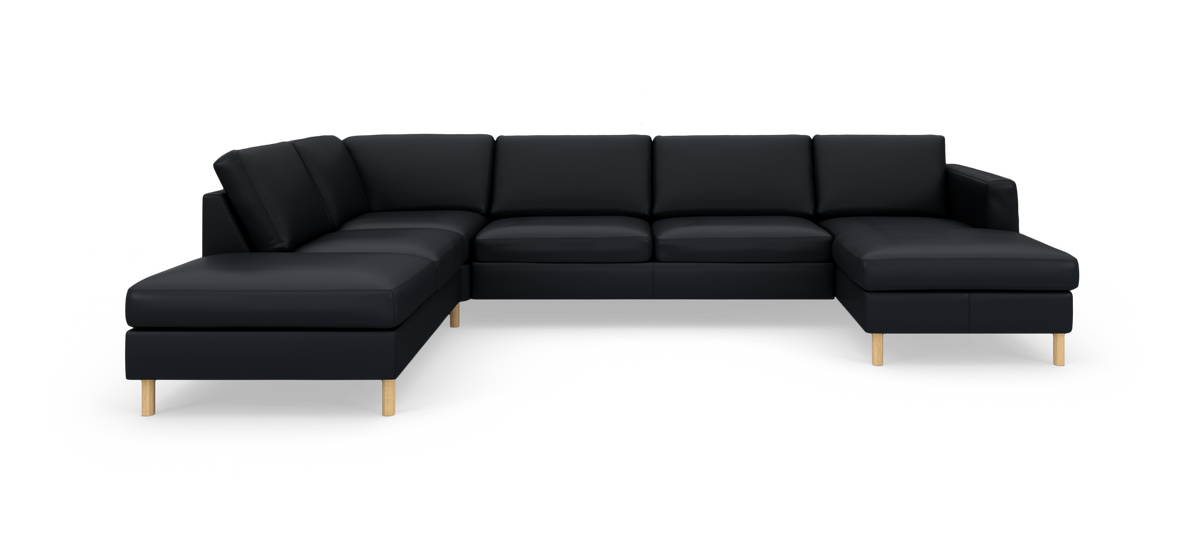 Sort modulsofa i L‑form med chaiselong i begge ender og lyse træben, frilagt på hvid baggrund.