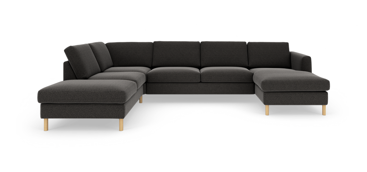 Mørkegrå U‑sofa med chaiselong i begge ender og lyse træben, frilagt på hvid baggrund.