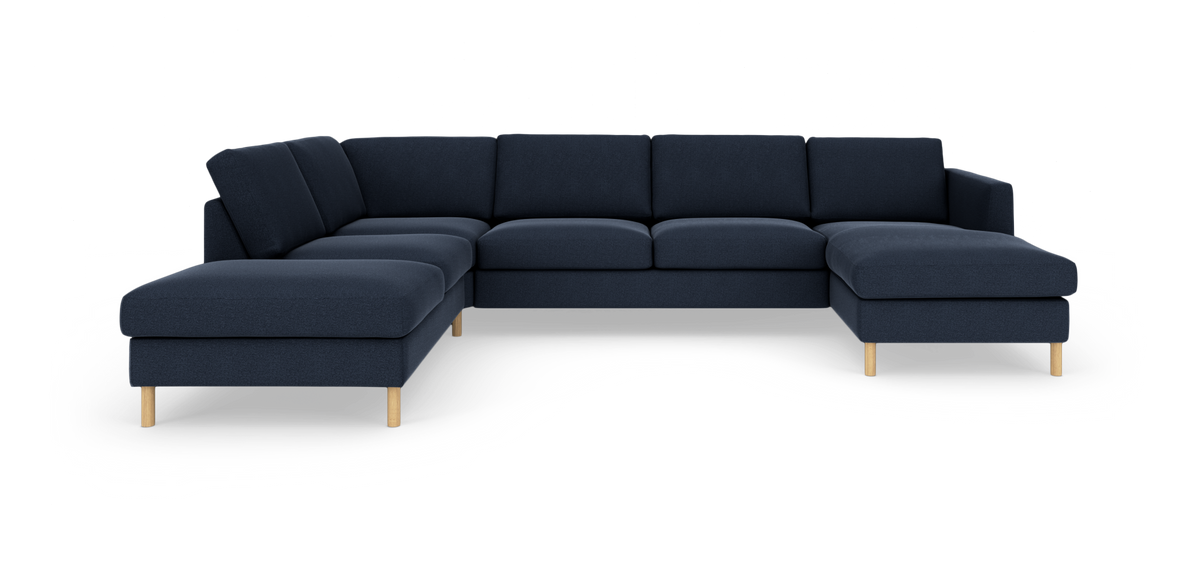 Mørkeblå modulsofa i L-form med chaiselong på højre side, træben, fritlagt mod hvid baggrund.