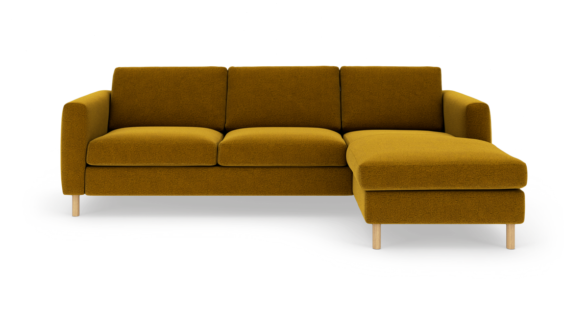 Sennepsgul L‑formet sofa med højre chaiselong på træben, frilagt i studie.