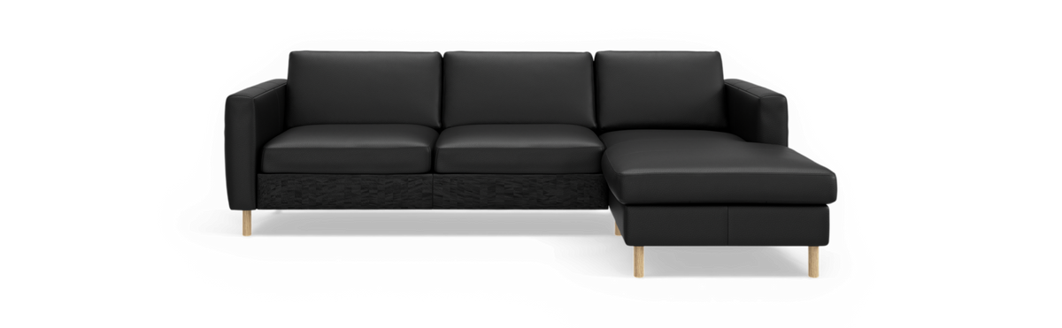 Sort modulsofa med højre chaiselong og træben, frilagt mod sort baggrund i frontvisning.