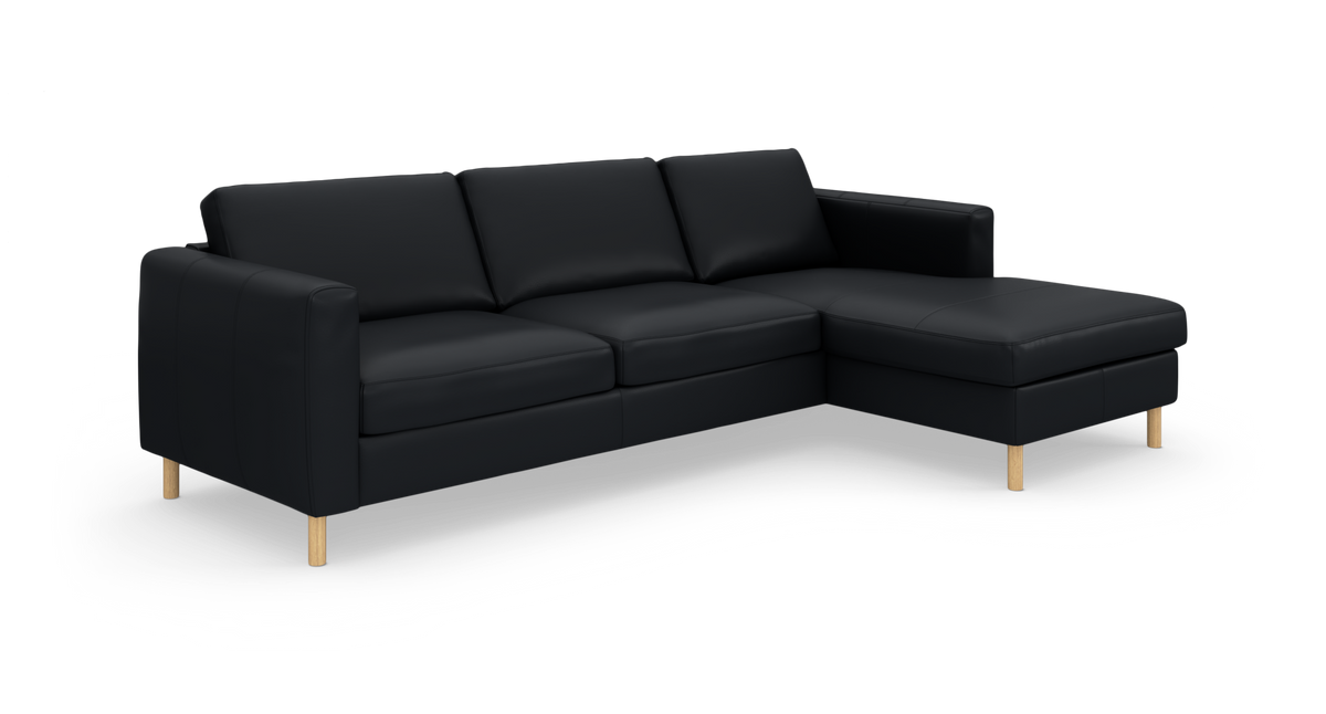 Sort hjørnesofa med chaiselong til højre på studiebaggrund.