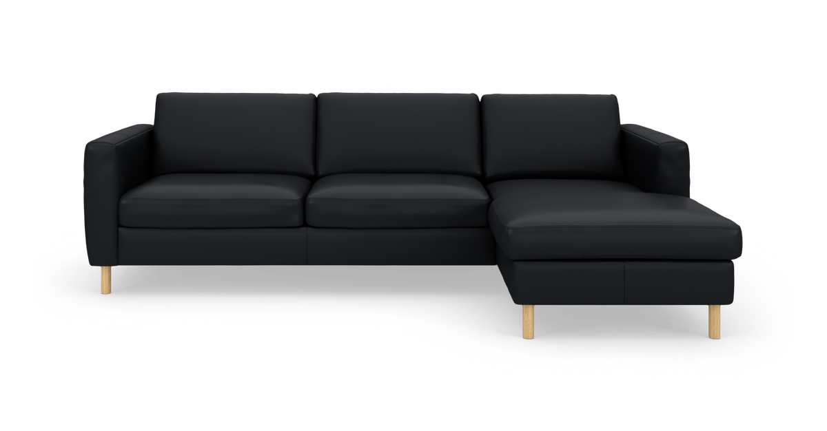 Sort hjørnesofa med chaiselong til højre og runde træben, frilagt på hvid baggrund.