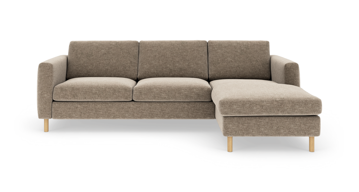 Beige hjørnesofa med chaiselong til højre, træben og bløde sædehynder på hvid baggrund.
