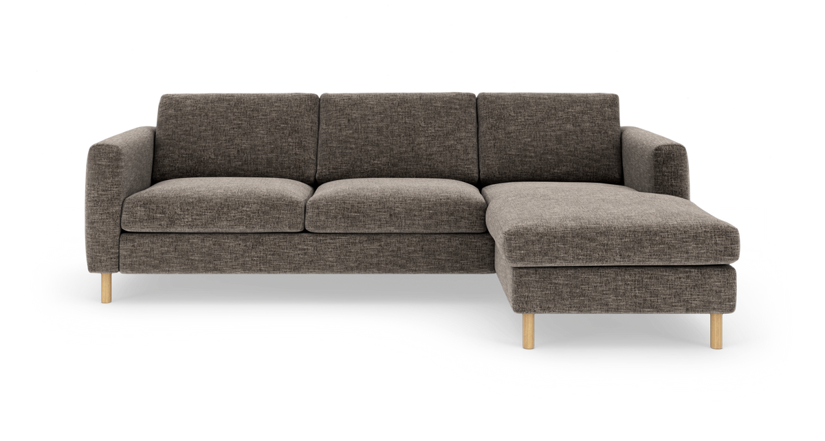 Mørkegrå hjørnesofa med chaiselong til højre og lyse træben, frilagt på hvid baggrund.