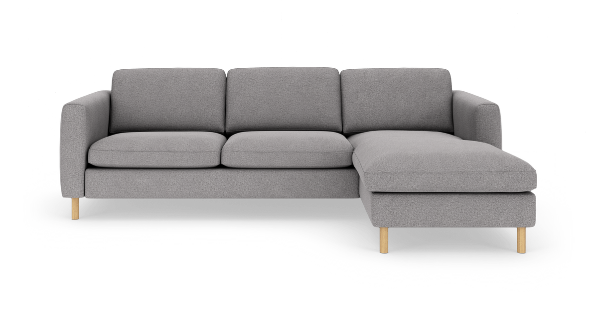 Grå hjørnesofa med chaiselong til højre på lys studiobaggrund.