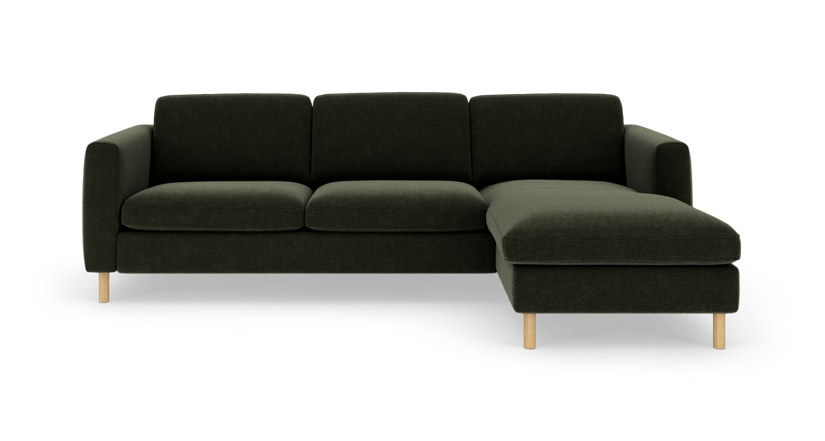 Mørkegrøn hjørnesofa med chaiselong til højre og lyse træben, frilagt mod hvid baggrund, frontvisning.