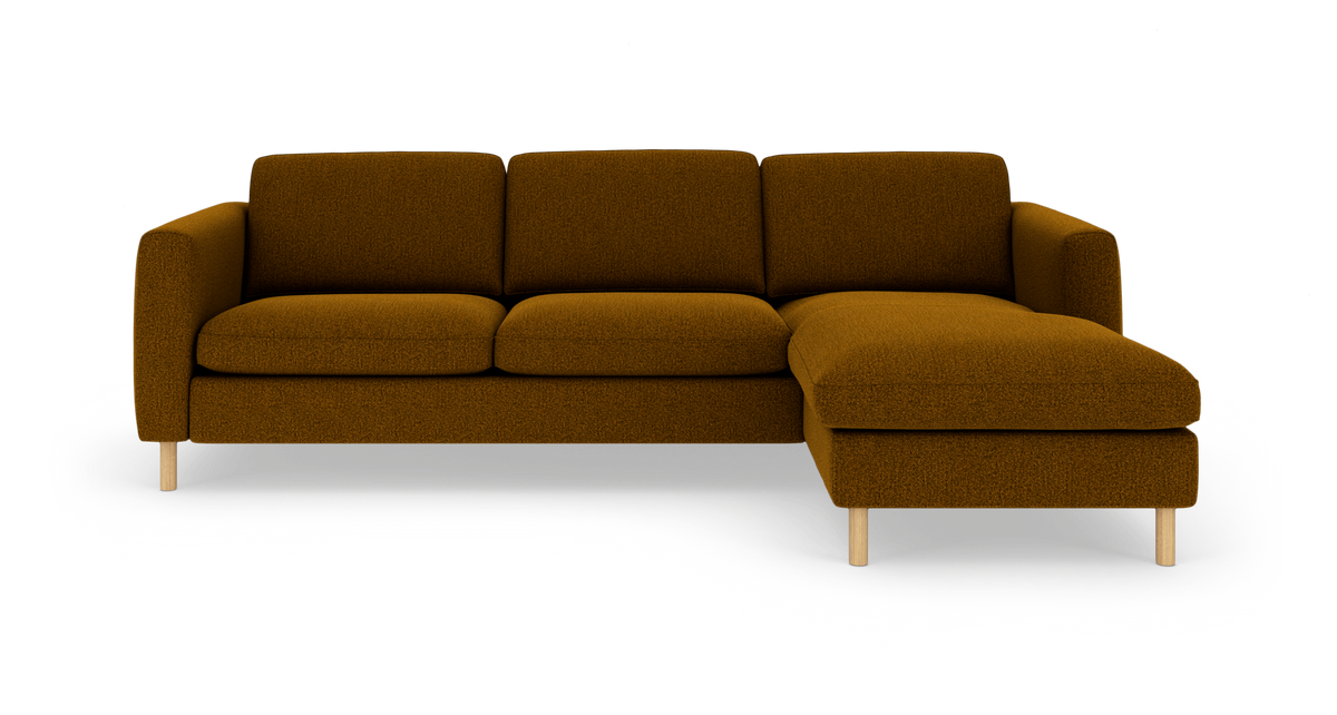 Modulsofa med chaiselong højre i sennepsbrun tekstil med lyse træben, frilagt på hvid baggrund.