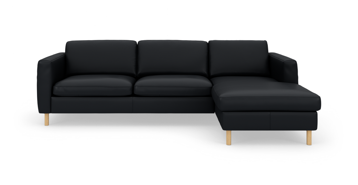 Sort hjørnesofa med chaiselong til højre og lyse træben på ren studiebaggrund.
