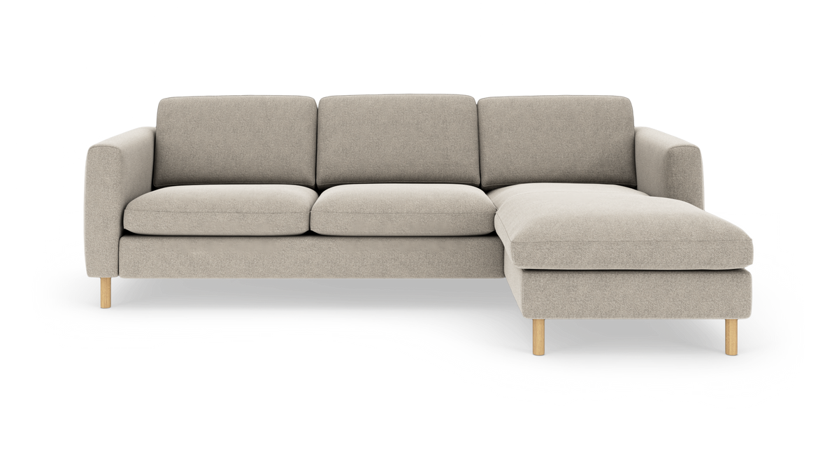 Beigefarvet hjørnesofa med chaiselong til højre og lyse træben, frilagt på hvid baggrund.